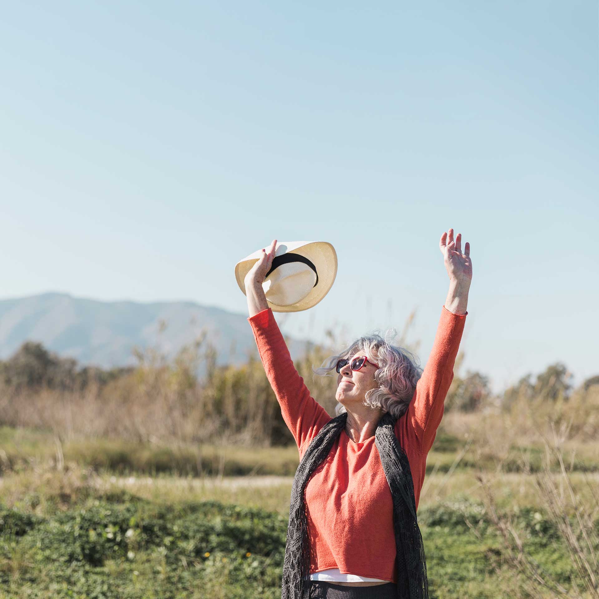 Eine Rentnerin hebt die Arme zum Himmel